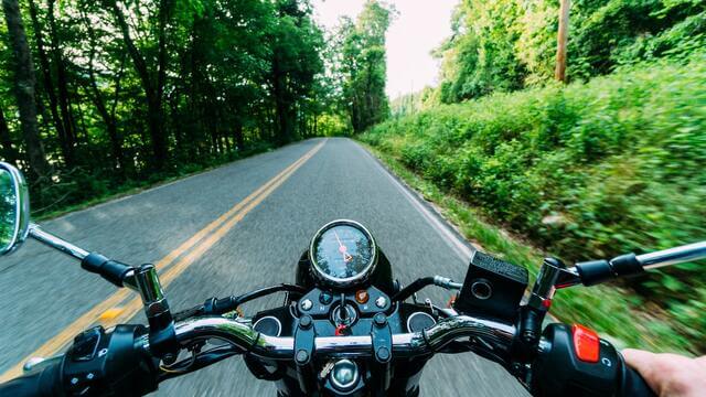 View of the motorcycle handlebars while someone is riding it